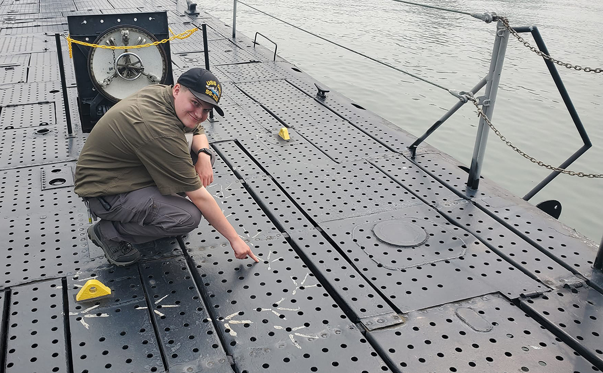 Ben Yanke on deck of the U.S.S. Cod checking out the muddy tracks of a seabird that visited the submarine.