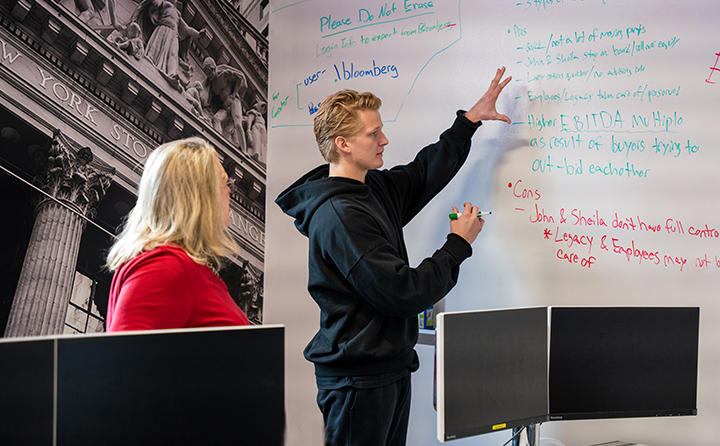 Dane McNulty '24 (right), talks through a finance project with Carmel Boyer School of Business dean Dr. Susan Kuznik (left) in BW’s Bloomberg Business Research Center.